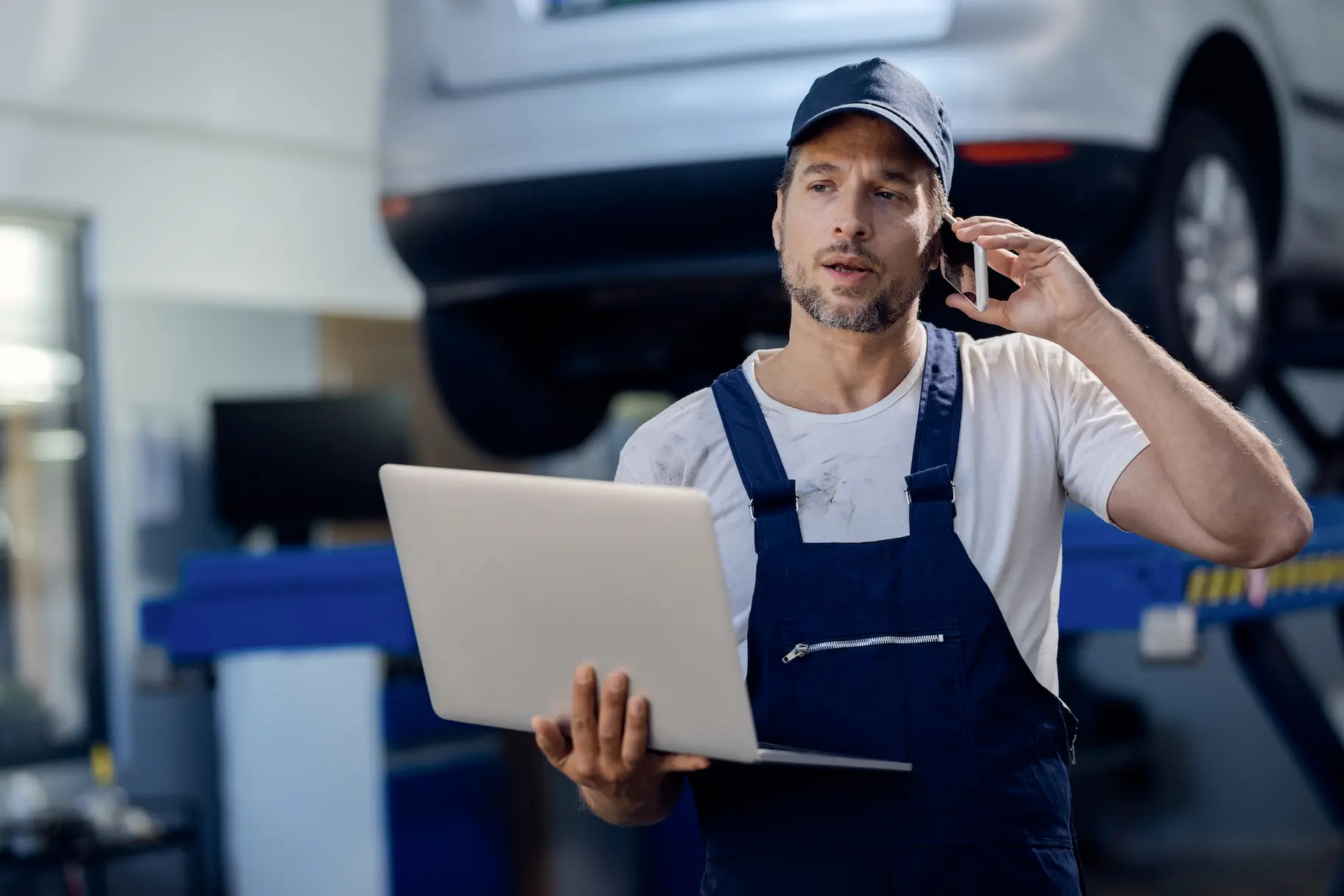 Mechanic on the phone with a laptop in hand