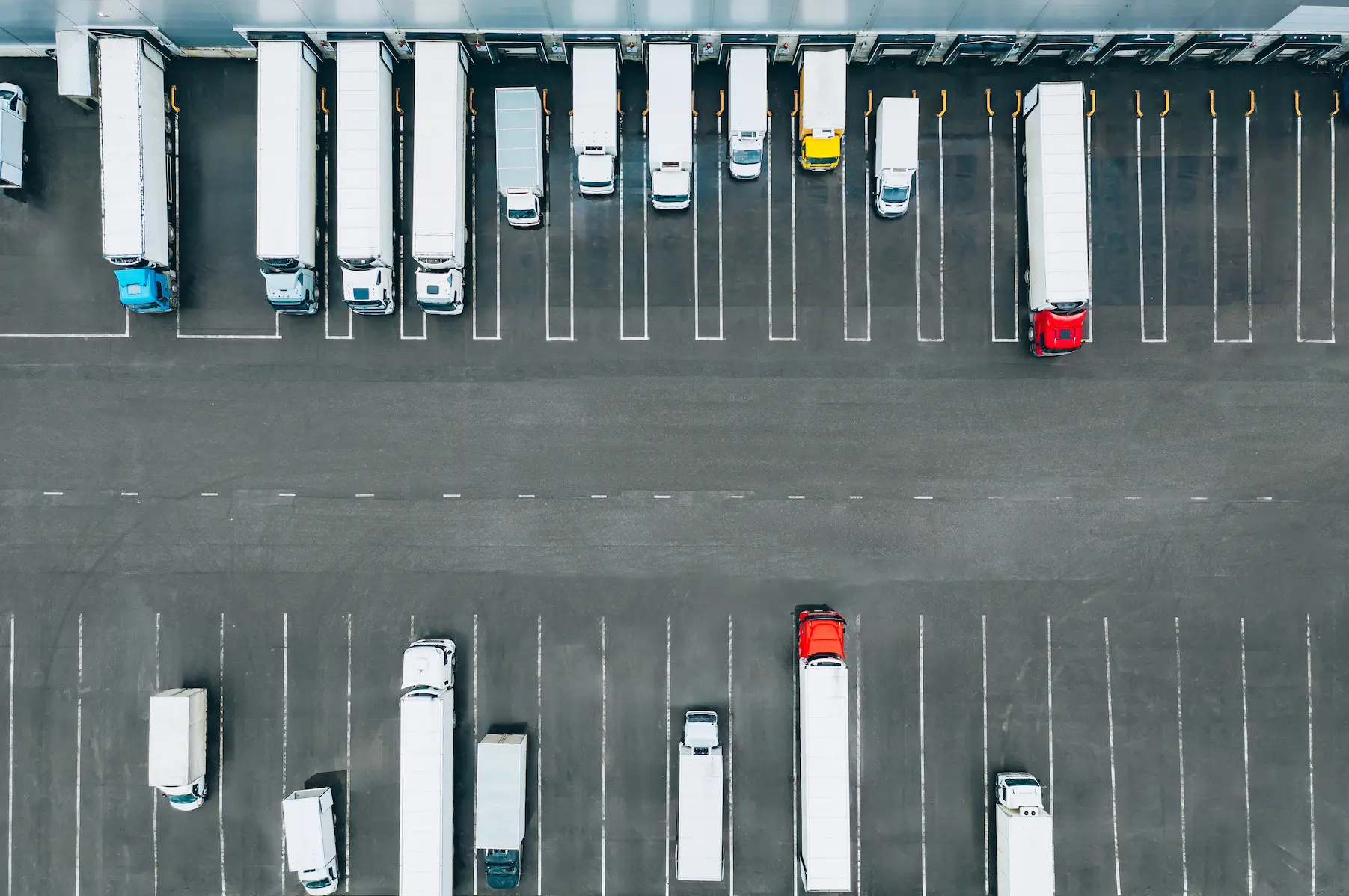 Aerial view of delivery trucks and trailers parked at a commercial loading dock and fleet staging area